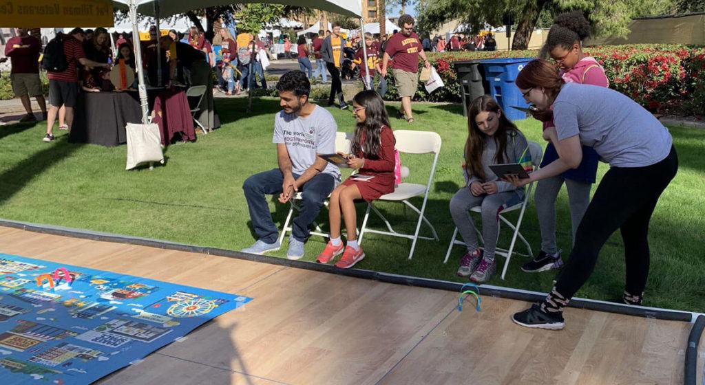 IgnitED Lab student workers help some kids navigate Sphero robots with a tablet