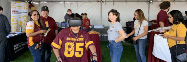 IgnitED Labs student worker and visitors watch a kid wearing VR goggles.