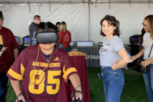 IgnitED Labs student worker and visitors watch a kid wearing VR goggles.