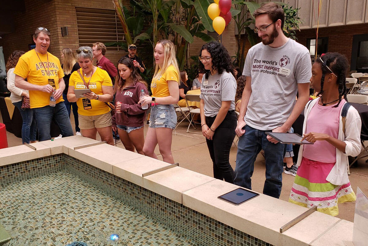 IgnitED staff looks on as visitors control Sphero robots in the water.