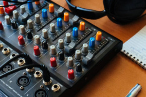 A table in a podcast studio with a notepad, mixing board and headphones